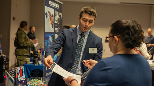 Student handing resume to employer at job fair